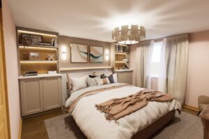 Cozy bedroom with a double bed, beige linens, built-in shelves, soft lighting, and a window with beige curtains.